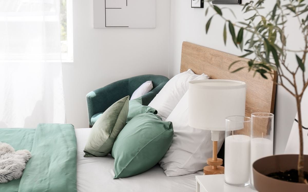 Chambre lumineuse aménagée, lit et coussins verts